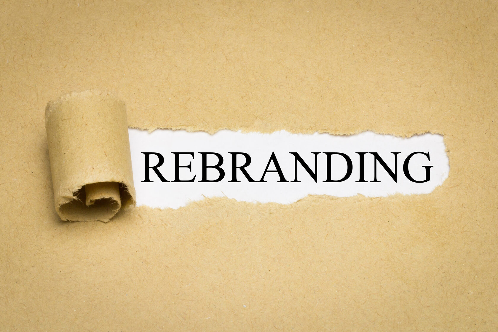 Слово REBRANDING проступает сквозь разорванную крафт-бумагу